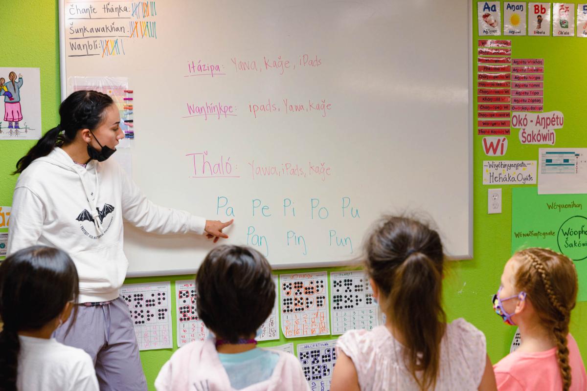 A teacher shows first-grade students how to pronounce vowels in the Lakota language