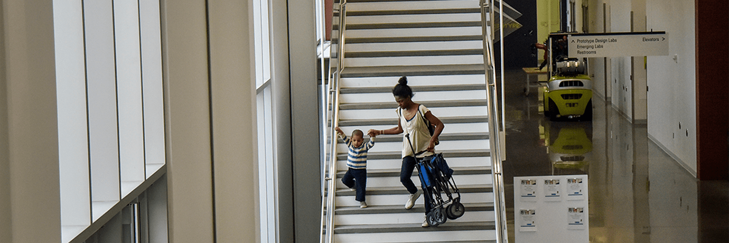 women holding a stroller and walking down a long staircase with her child