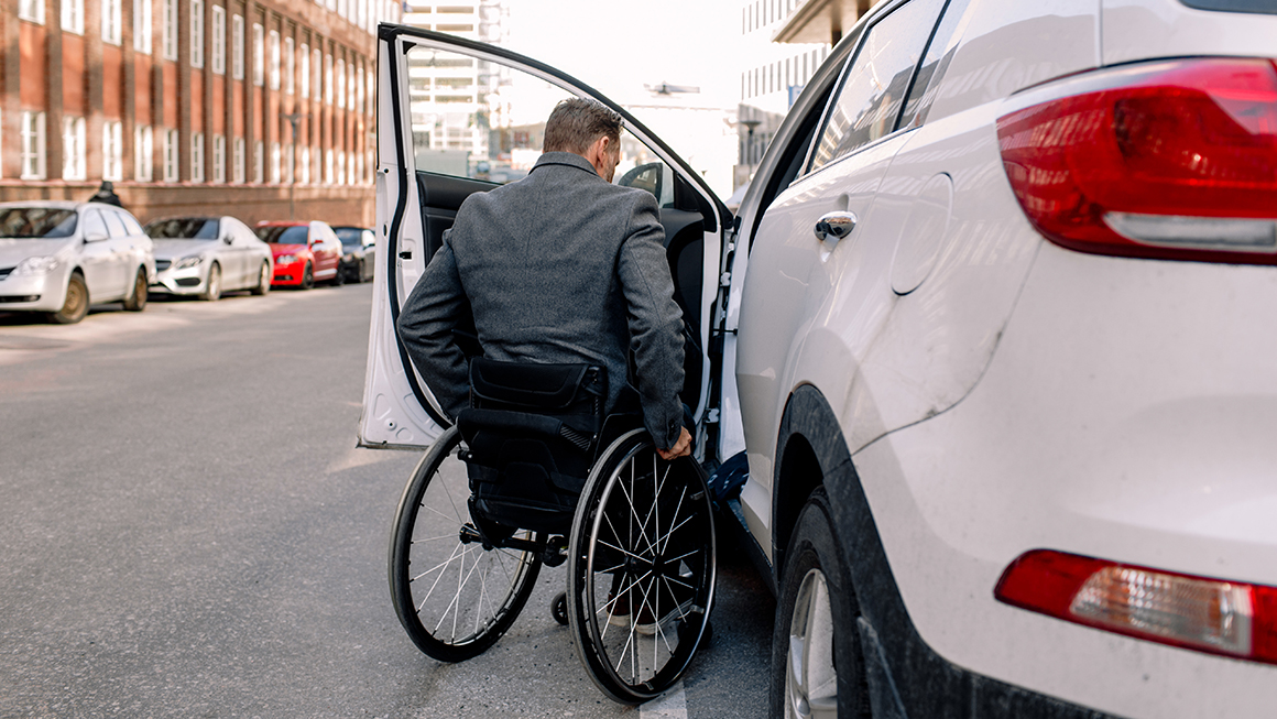 Man in a wheelchair getting in a car
