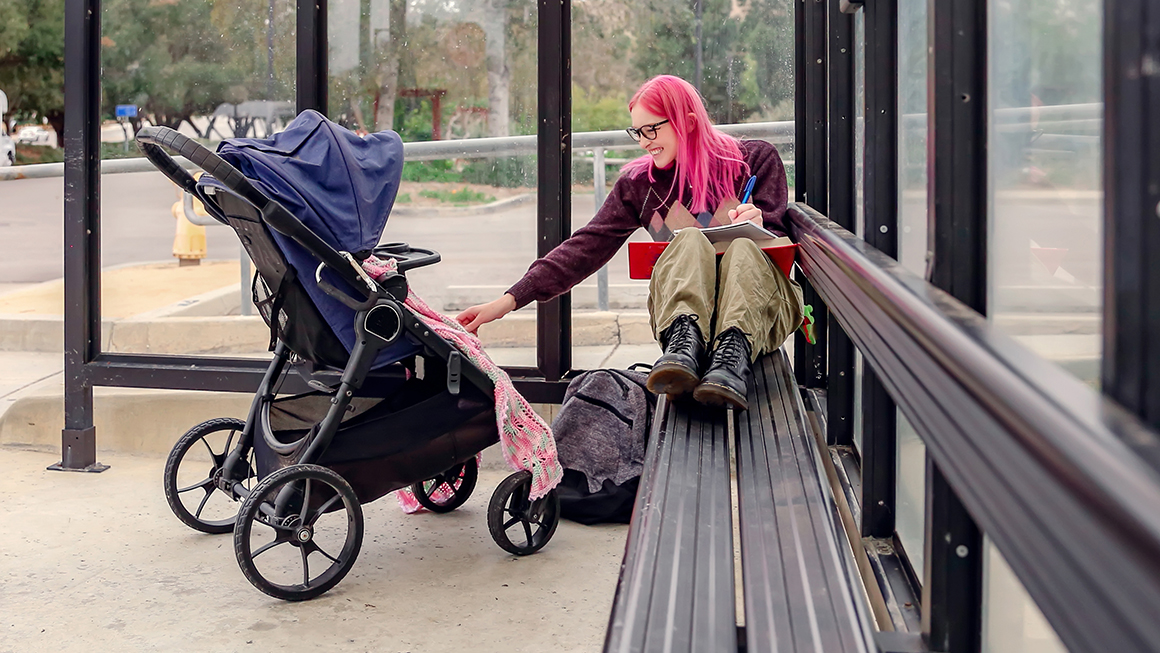 A mother and her baby at a bus stop. 