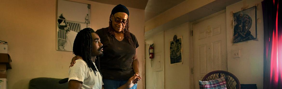 mother and son sitting in apartment looking worried