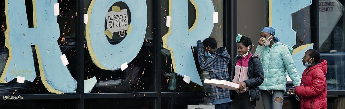 A group passes by a sign in the window of Busboys & Poets in Ward 8 in Anacostia, in Washington, DC.