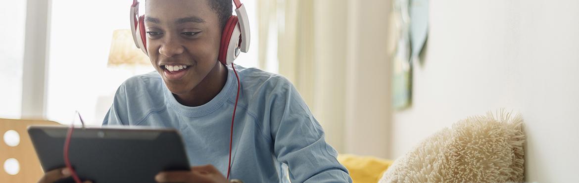 Black boy in headphones using digital tablet