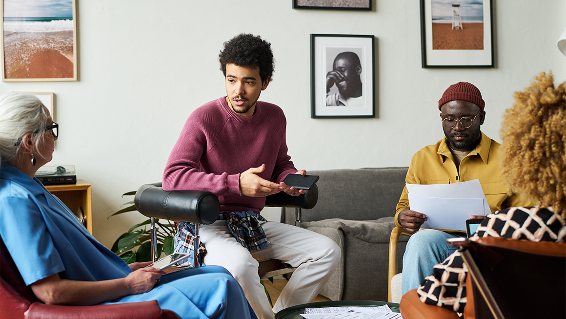 Young multi-ethnic economist explains something to mature coworkers