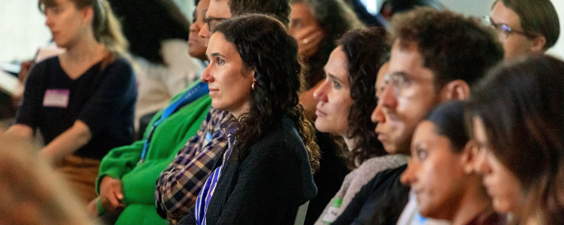 A conference crowd looks to the stage with meaningful attention.