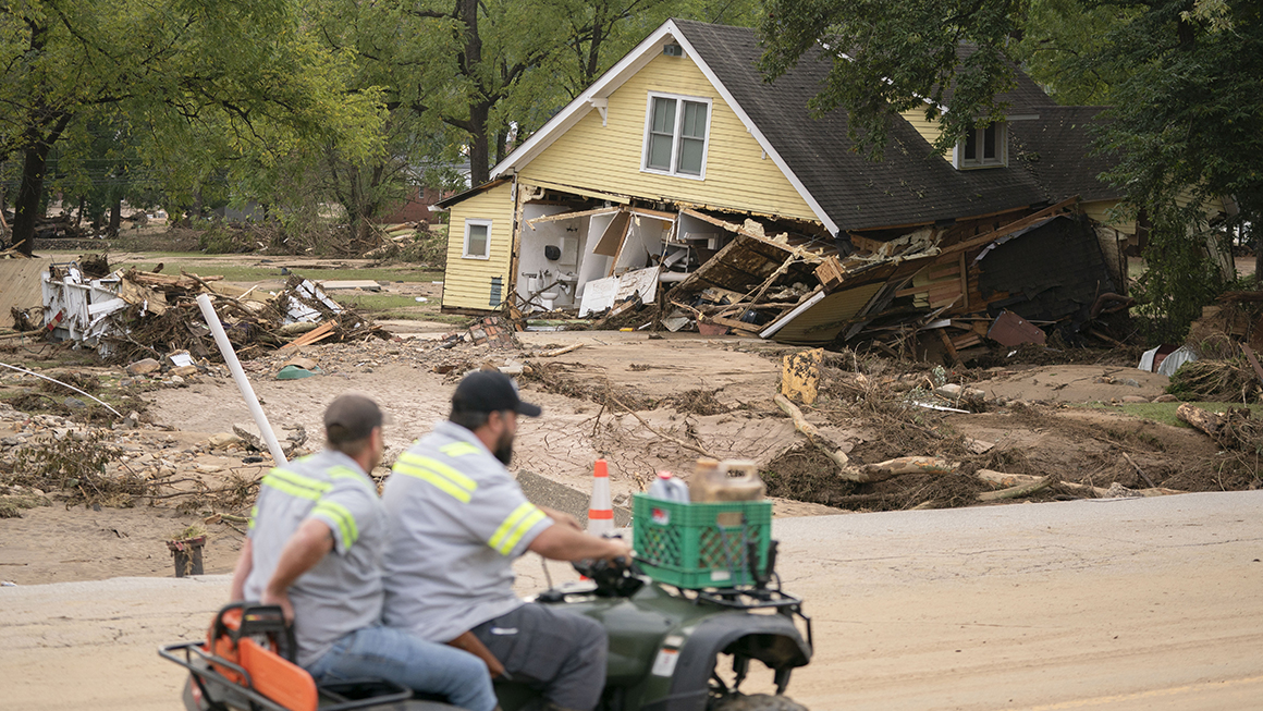photo of men on a four wheeler passing a storm-damaged house along Mill Creek in the aftermath of Hurricane Helene in September 2024
