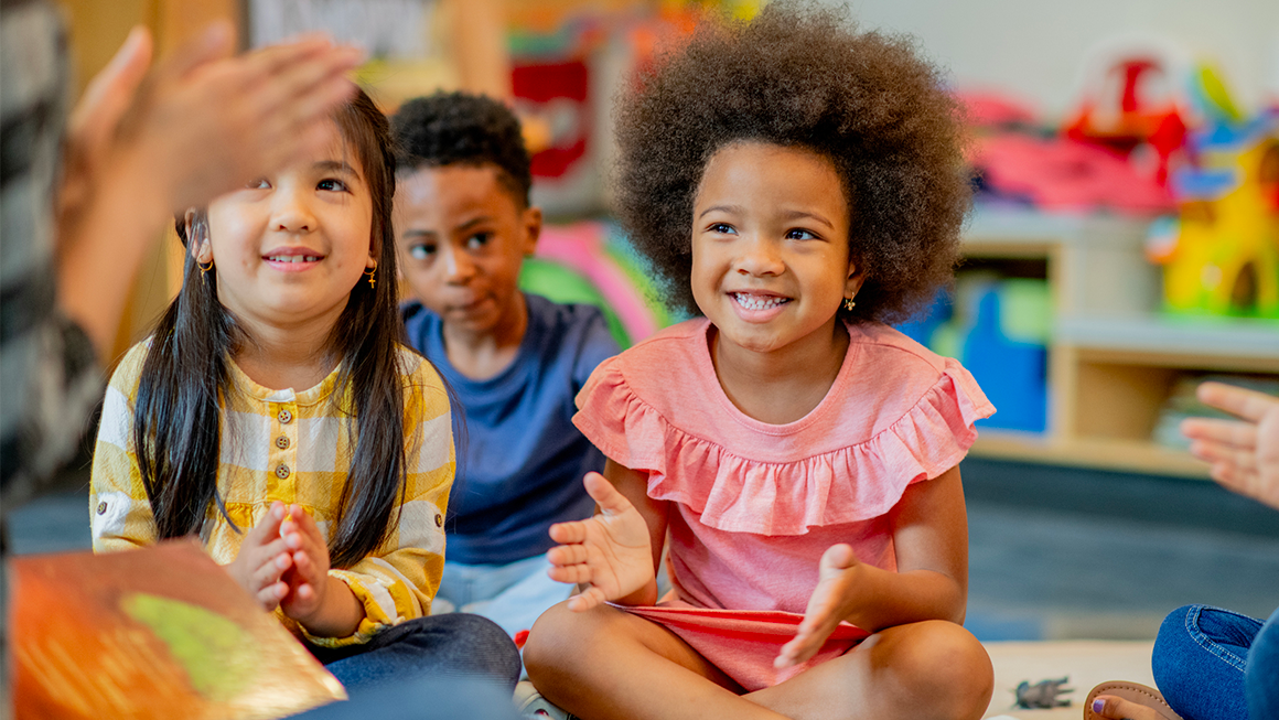 Two young children listen to their instructor and happily clap along. 
