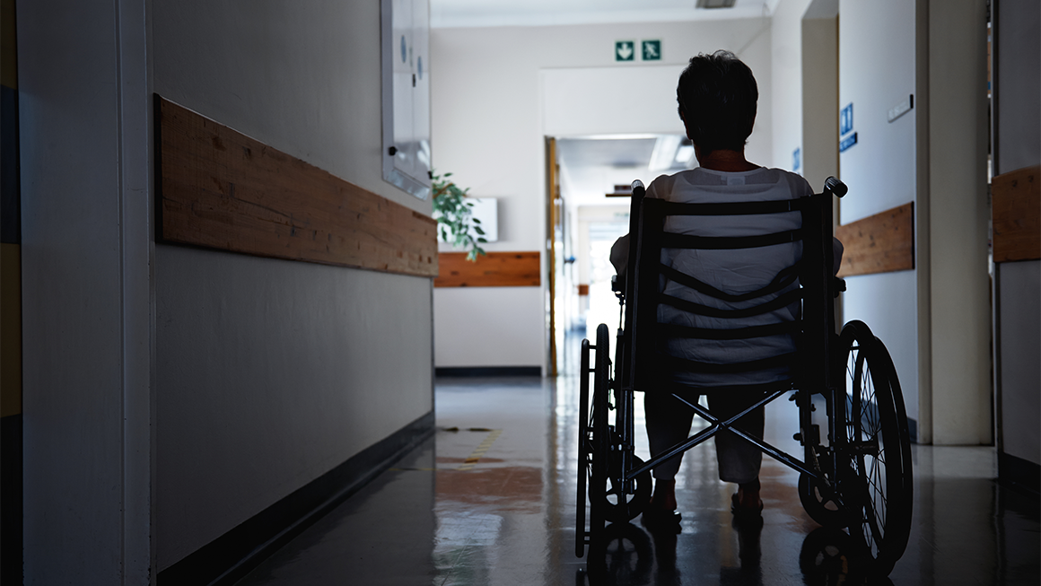 A woman on a wheelchair in a hallway.