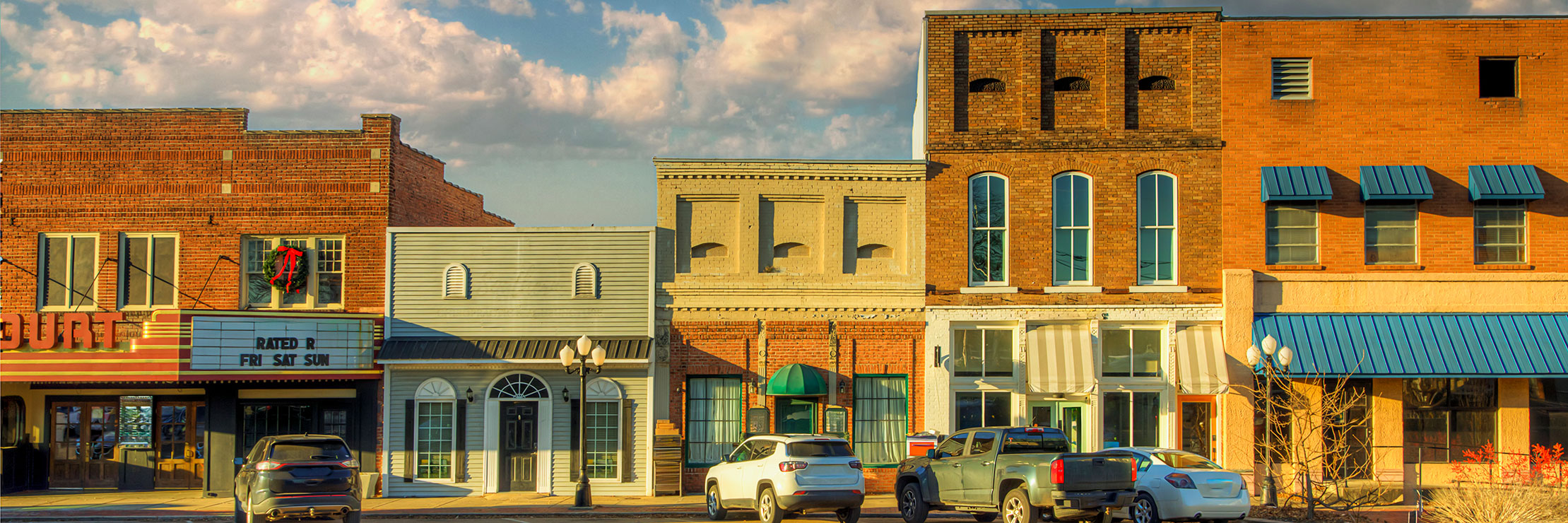 Storefronts and parked cars along a town’s main street.