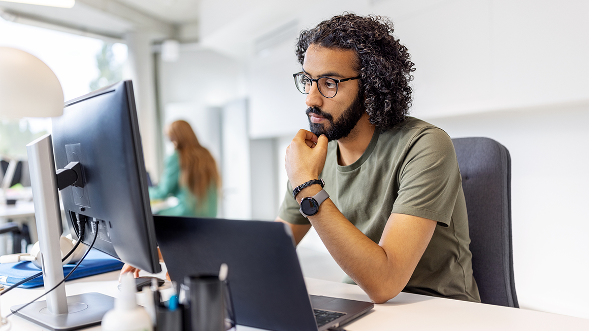 Image of a young worker of color looking at a computer screen.