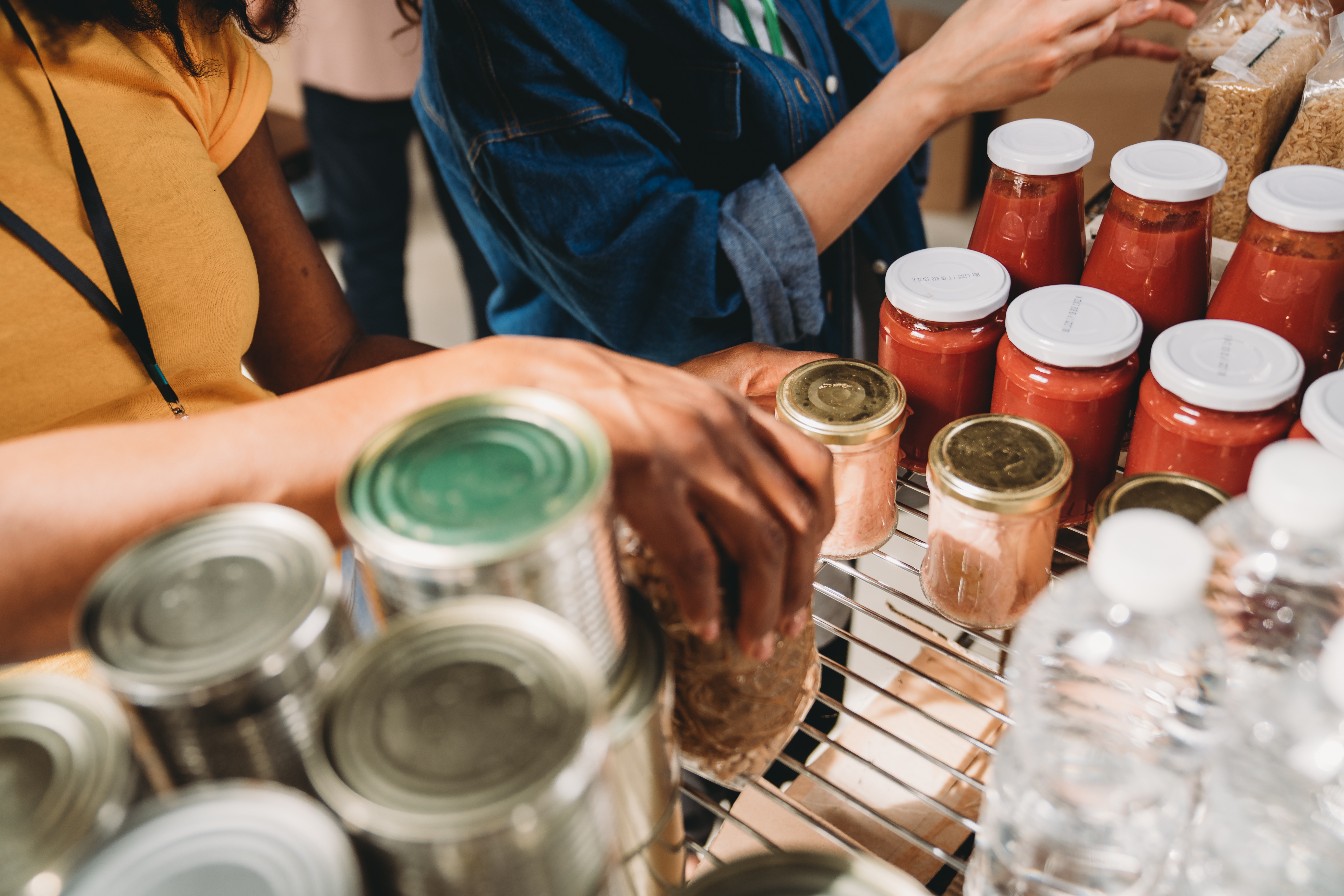 Photo of volunteers stacking items on a shelf at a food pantry.