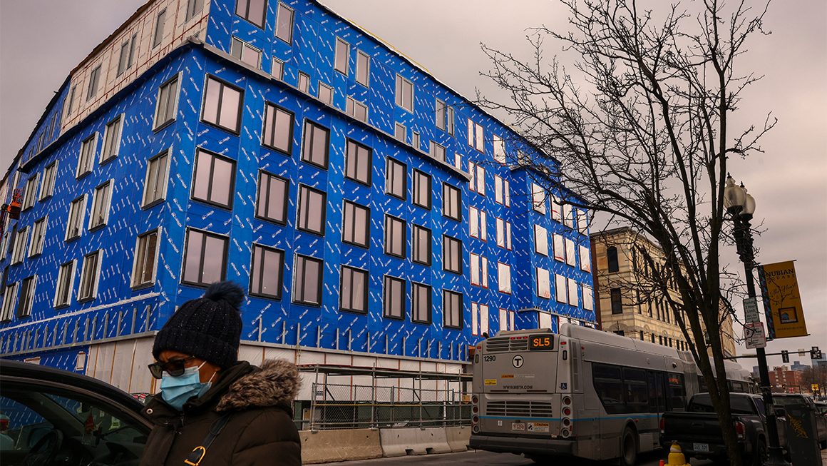 Photo of a pedestrian walking by a mixed-income housing project in Boston.