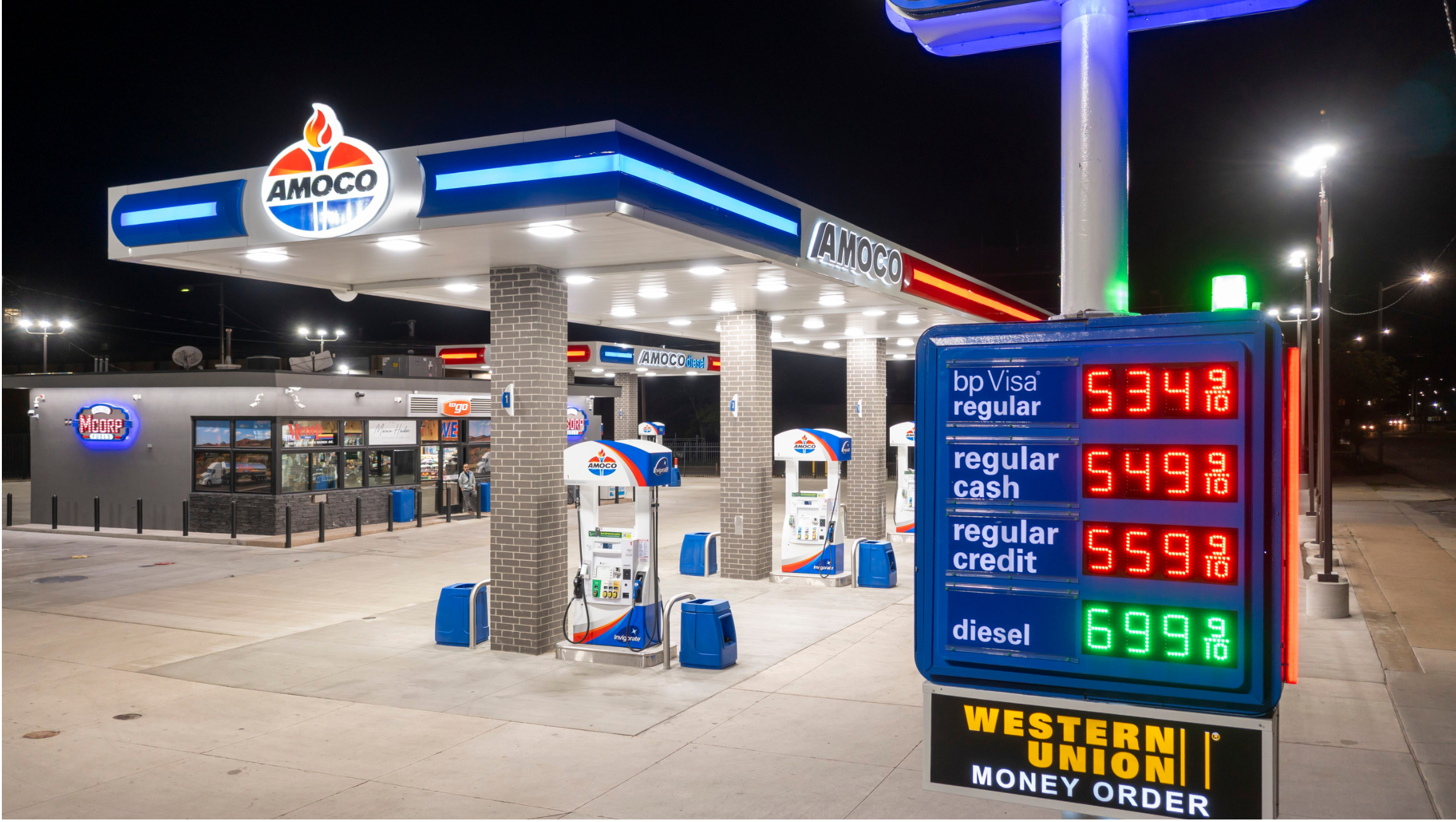 Amoco gas station with illuminated fuel price sign at night.