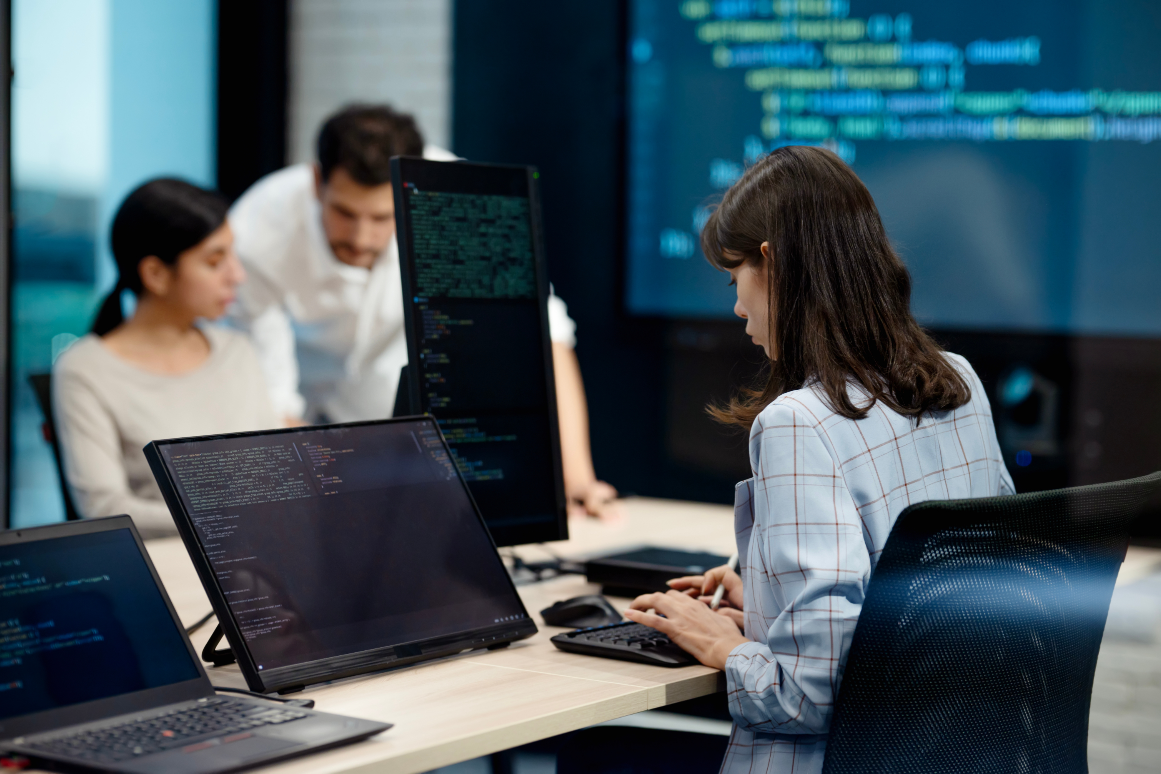 People working at computers with coding screens.