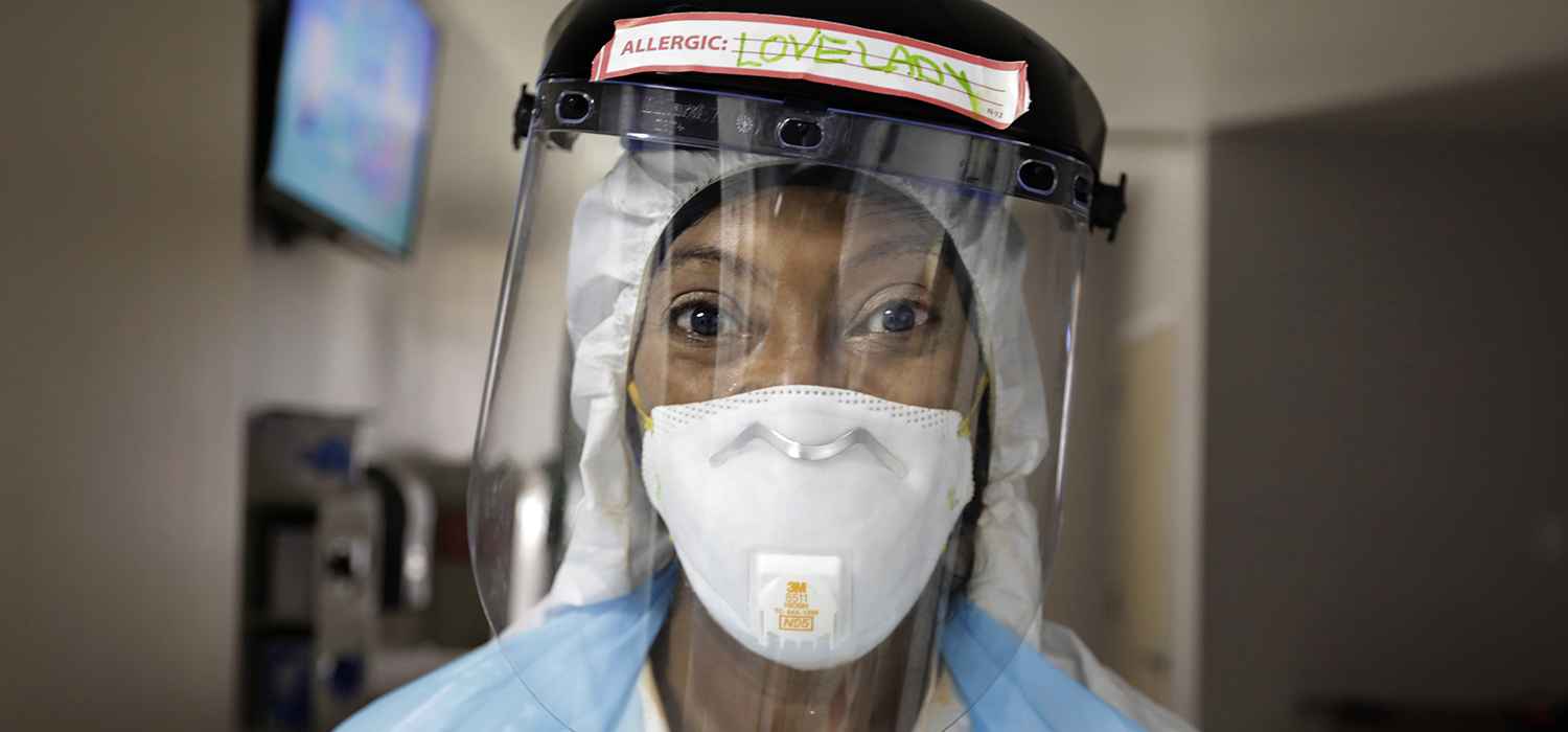 A nurse stares at the camera wearing a mask and face shield 