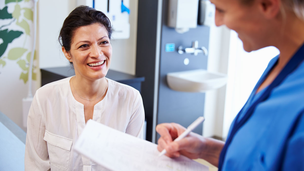 Female Patient And Doctor Have Consultation In Hospital Room