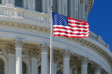 US Capitol Building dome detail with waving national flag.