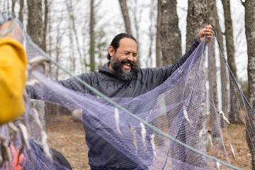 Joe Van Alstine, regional Food Distribution Program on Indian Reservations director and citizen of the Little Traverse Bay Bands of Odawa Indians, holds up a net full of caught smelt.