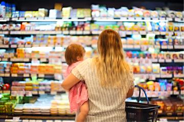 photo of woman standing holding child in front of grocery aisle