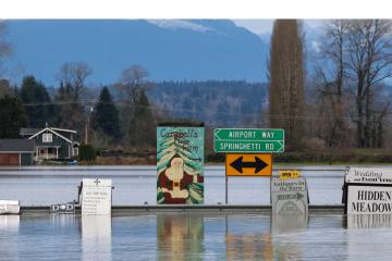 A sign for a Christmas tree farm is pictured as flood waters from the Snohomish River cover Marsh Road off State Route 9 in Snohomish, Washington