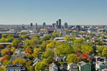 A high perspective shot overlooking a suburban neighborhood with lots of trees toward taller buildings downtown.