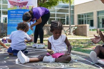 Four toddlers play with chalk outside