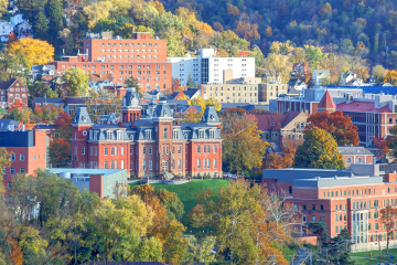 Photo of the University of West Virginia, with autumn foliage on the surrounding hills.