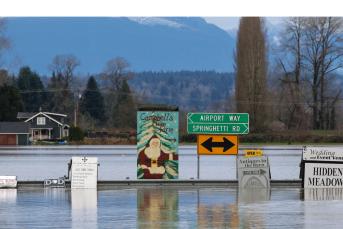A sign for a Christmas tree farm is pictured as flood waters from the Snohomish River cover Marsh Road off State Route 9 in Snohomish, Washington