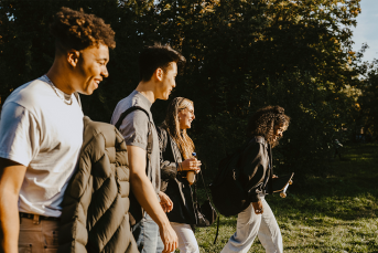 photo of happy male and female friends walking on road in park