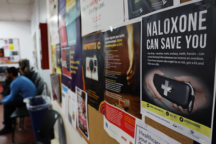 A sign for Naloxone hangs on a wall as students learn to put together a Naloxone spray gun in a class on opioid overdose prevention held by non-profit Positive Health Project on August 9, 2017 in New York City
