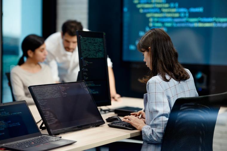 People working at computers with coding screens.
