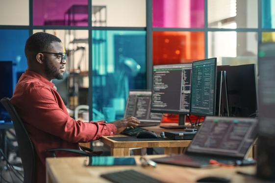 A professional working in front of multiple computer screens.