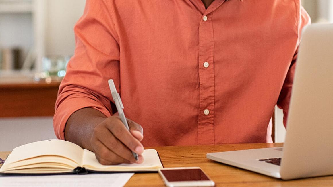 photo of person with laptop and notebook
