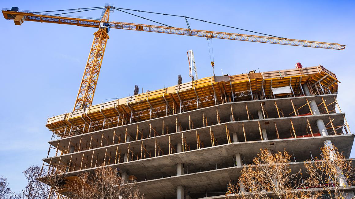 Multi-level concrete building under construction with tower crane