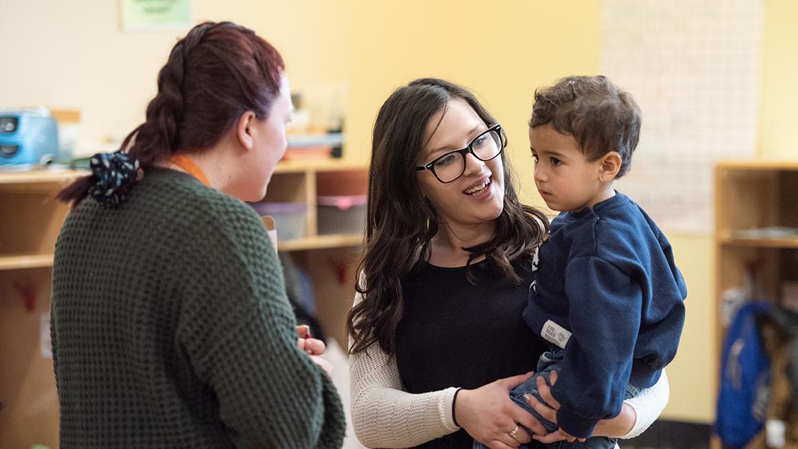 Mother holding Child while speaking to Administrator