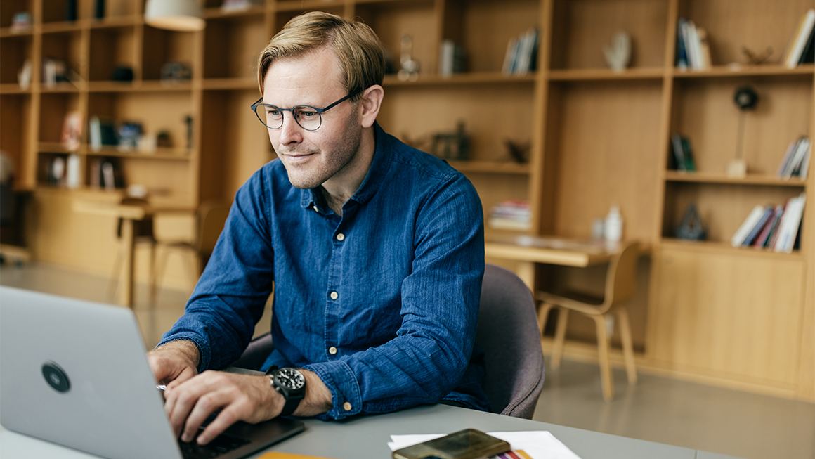 A man sits and types at a laptop