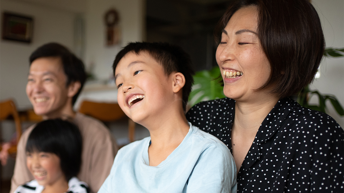 Family laughing together at home, showing joy and closeness in a warm, cozy setting.