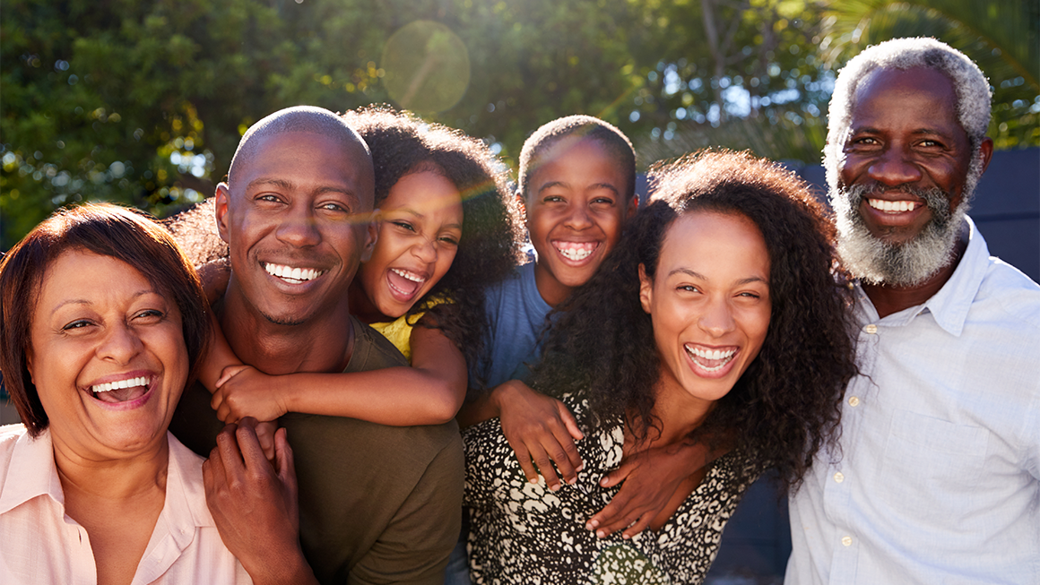 Outdoor Portrait Of Multi-Generation Family In Garden At Home Against Flaring Sun