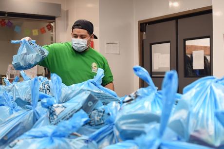 Volunteers help prepare bags of food to aid those in need during the coronavirus outbreak at the Arlington Food Assistance Center, on April 28, 2020, in Arlington, Virginia. (Photo by OLIVIER DOULIERY/AFP via Getty Images)