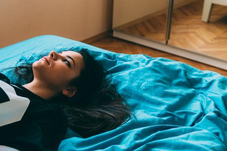 Young woman reclines on bed