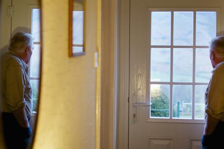 older man looks out window