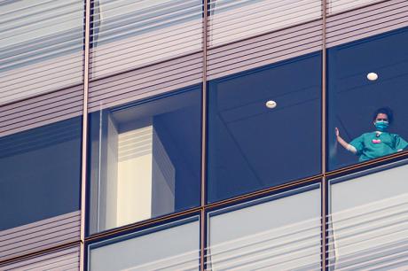 A medical worker watches from the window at NYU Langone Health hospital as people applaud to show their gratitude to medical staff and essential workers on the front lines of the coronavirus pandemic on May 10, 2020 in New York City.