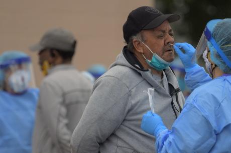 A health volunteer, right, uses a swab to collect a sample from the nose of 70 year old Richmond area resident Wayne Thorpe. This is part of the testing for covid-19 in a shopping center that services an area that has public housing in Richmond, VA.