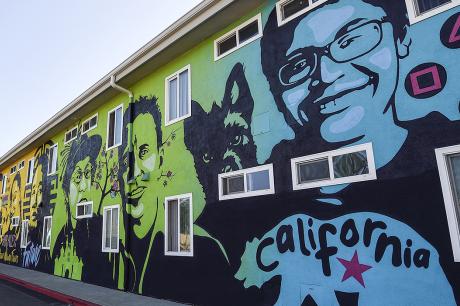 A mural features faces and quotes from residents of permanent supportive housing