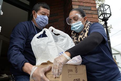Jessica Armijo distributes food and packages of donated goods to people in need outside the Pan Y Cafe in Chelsea, Massachusetts on April 14, 2020. 