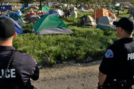  police officers keep an eye as city officials started clearing and cleaning the central lot of a homeless encampment