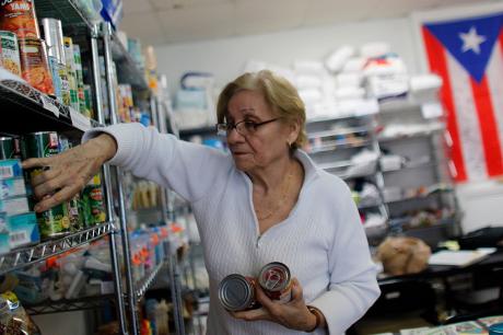 rma Ramos, 71, organises donated canned food into shelves at the Latino Leadership headquarters in Orlando, Florida on December 1, 2017.