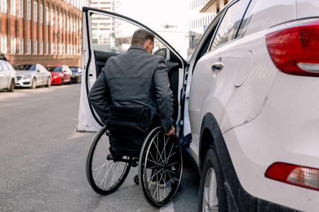 Man in a wheelchair getting in a car