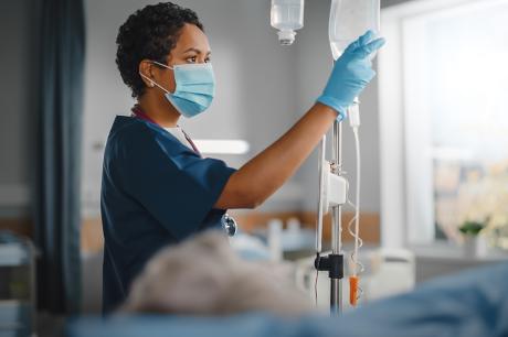 A nurse adjusting an IV bag. 