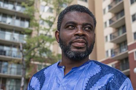 photo of African American man standing with housing in background